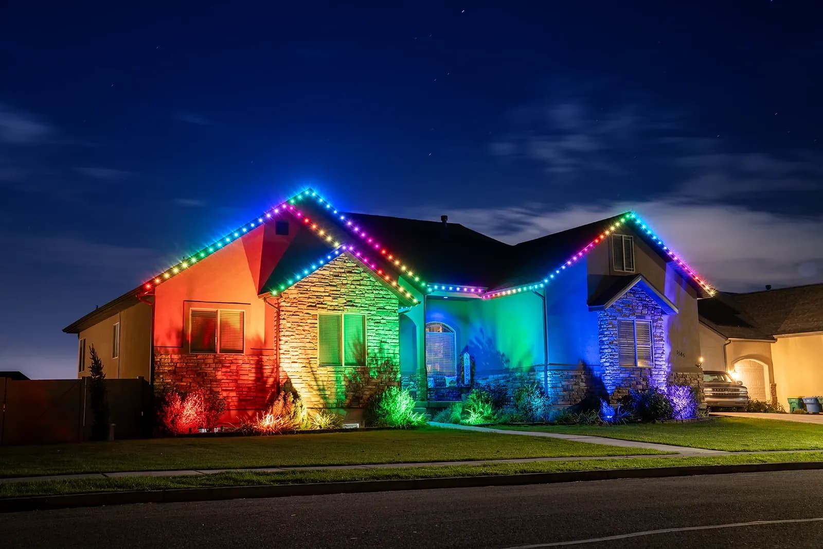 Rainbow permanent LED lights glowing along a roofline at night